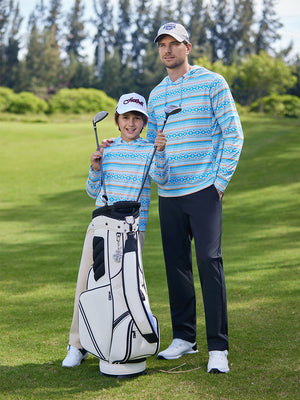 Son taking two clubs from golf bag on course, father standing nearby, wearing trendy print fleece hoodies in ethnic