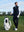 Model holding a golf club beside a golf bag on course, wearing print collar quarter zip golf vest in navy