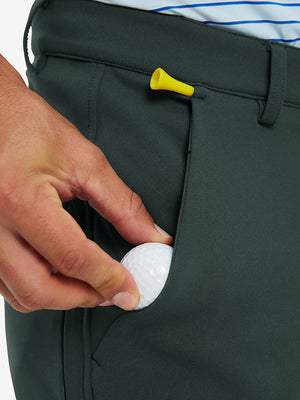 Model holding a golf club, wearing navy water-resistant zip up golf jacket in full-body view.