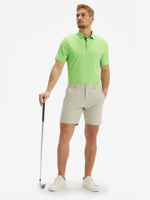 Full-body front view of model with a golf club wearing the turquoise green ventilated pique performance polo on the course