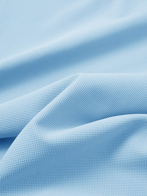 Close-up texture of light blue waffle texture 1/4 zip pullover fabric showing detailed waffle knit material and weave.