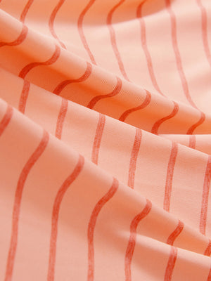 Close-up texture of peach amber/calypso coral non-curl ribbed collar striped polo shirts fabric showing striped weave detail