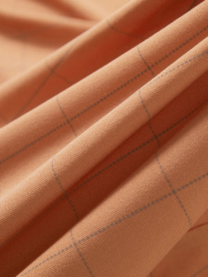 Close-up texture of orange adobe reflective performance reflective checked collar golf shirt fabric showing weave detail.