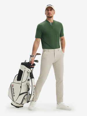 Full-body front view: model in army green moisture-wicking short sleeve henley shirt holding golf bag.