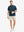 Detail shot with model holding a takeaway drink and sunglasses, featuring the BLUE INDIGO polo’s side vent.