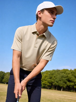 Model in pre-swing golf pose wearing beige ventilated pique performance polo